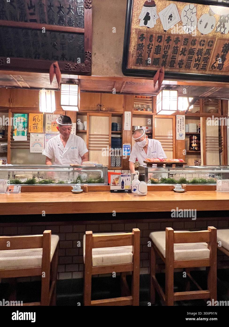 Chef plating a single piece of nigiri with tweezers