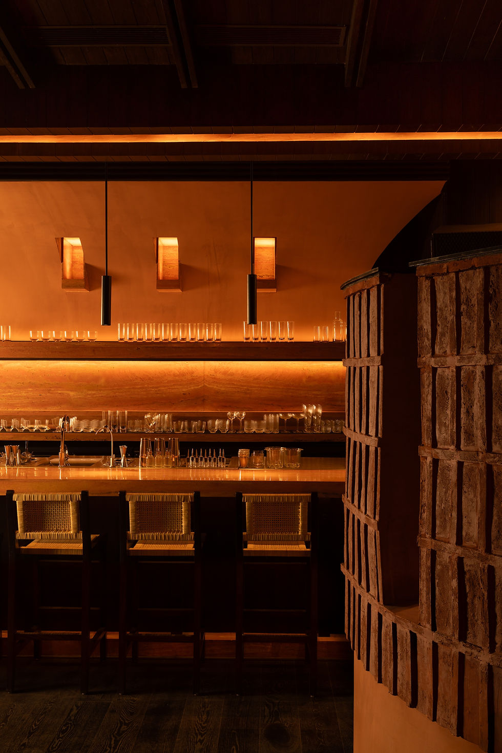 Wooden counter seats at a quiet sushi bar with warm lighting