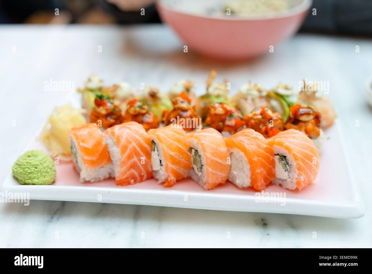 A bowl of vinegared sushi rice being mixed with a wooden paddle