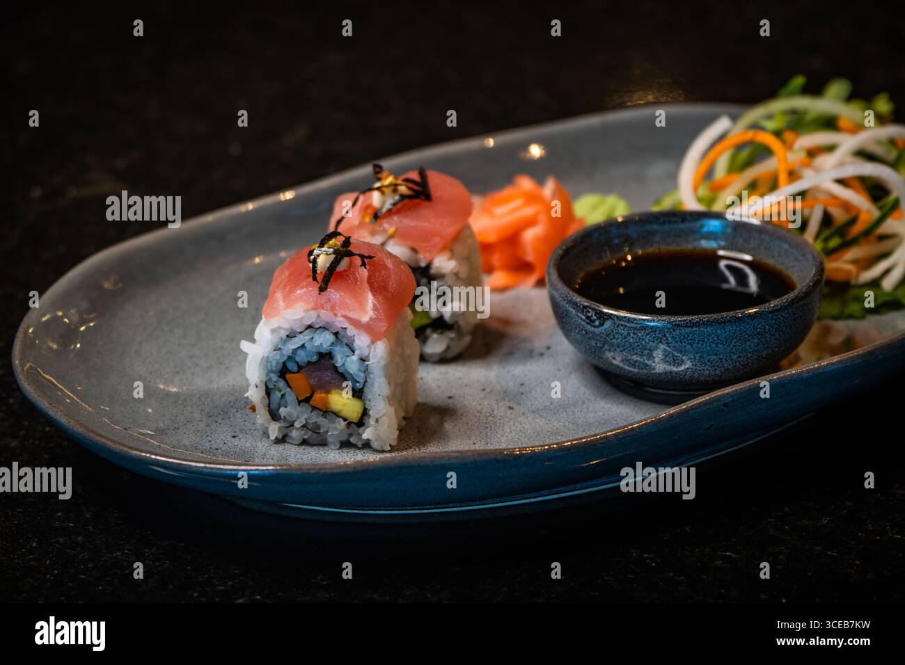 A sushi roll cut into eight pieces on a black plate