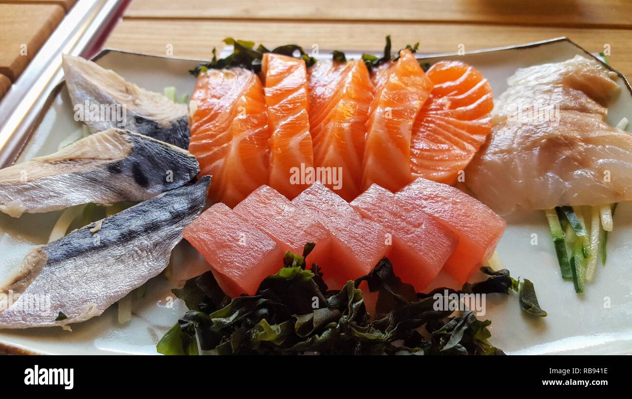 Slices of fresh salmon and tuna laid out on a dark ceramic surface